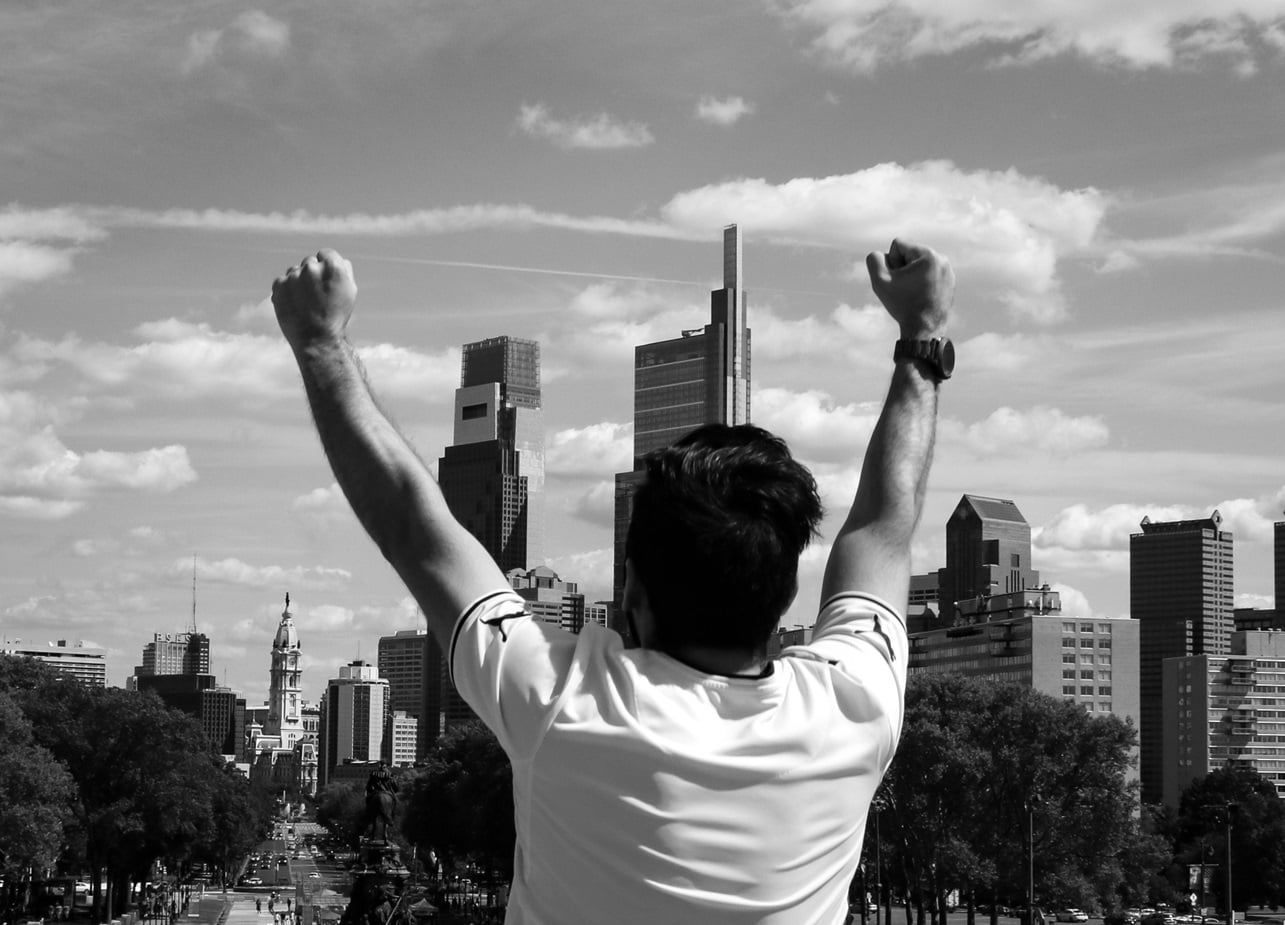 digital presence - man on top of city sky line raising hands in triumph